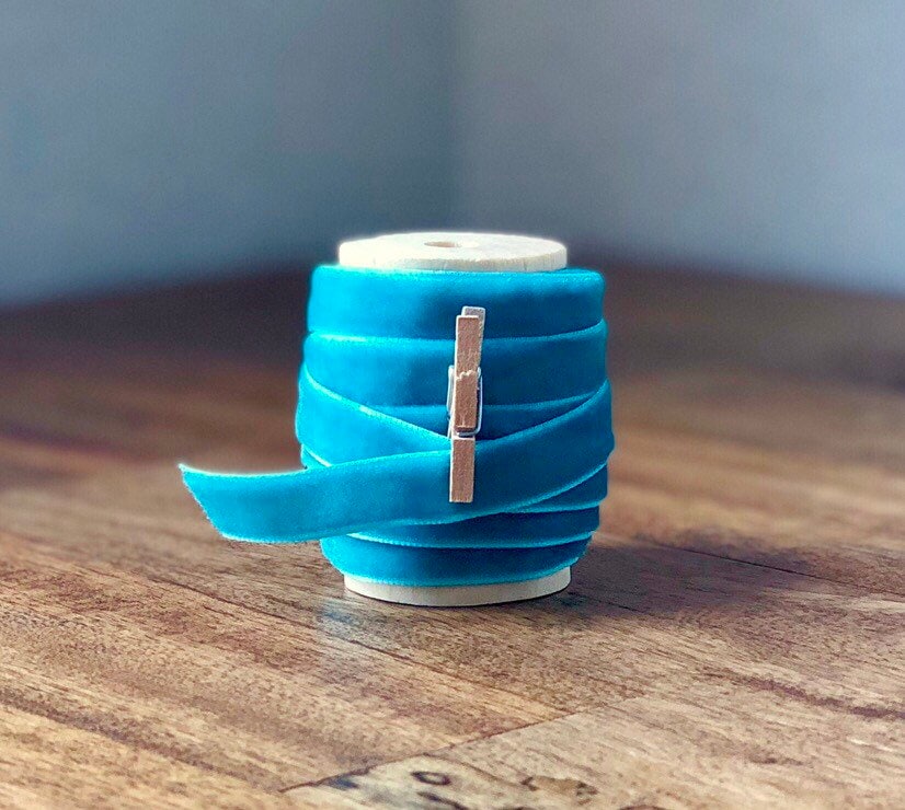 Teal blue velvet ribbon on wooden spool