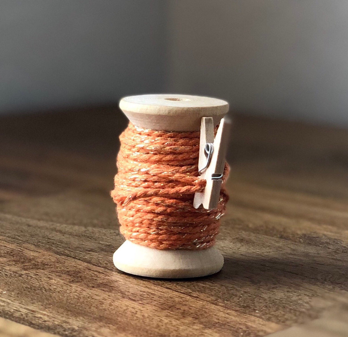 Orange and gold glitter twine on wooden spool