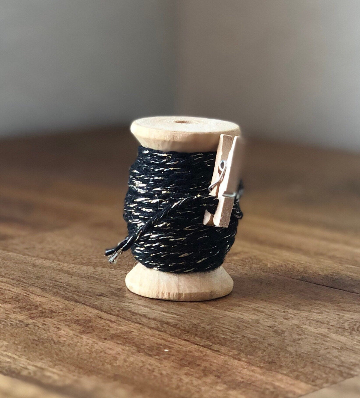 Black and gold glitter twine on wooden spool