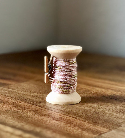 Pale pink and gold nylon cord on wooden spool