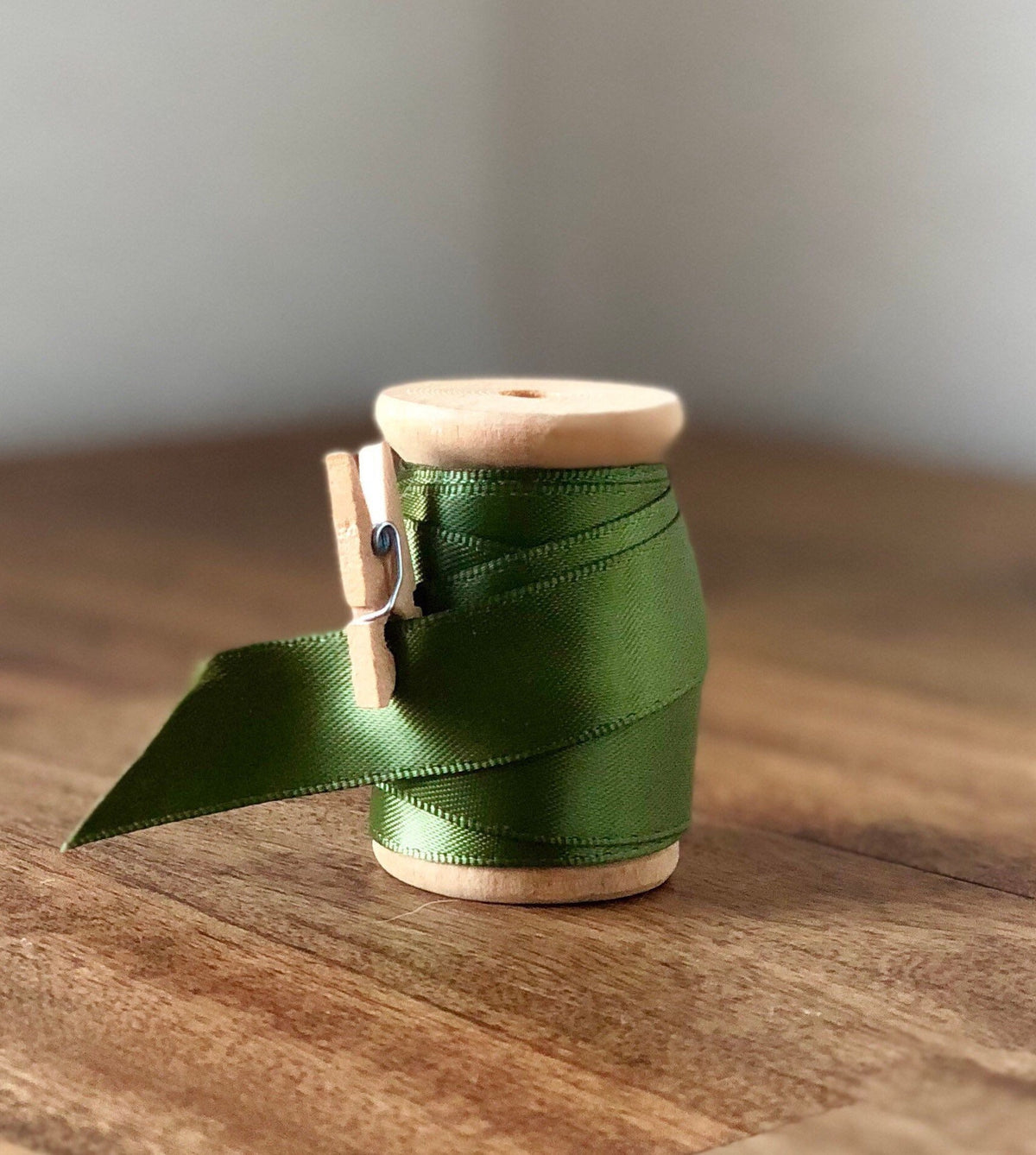Moss green satin ribbon on wooden spool