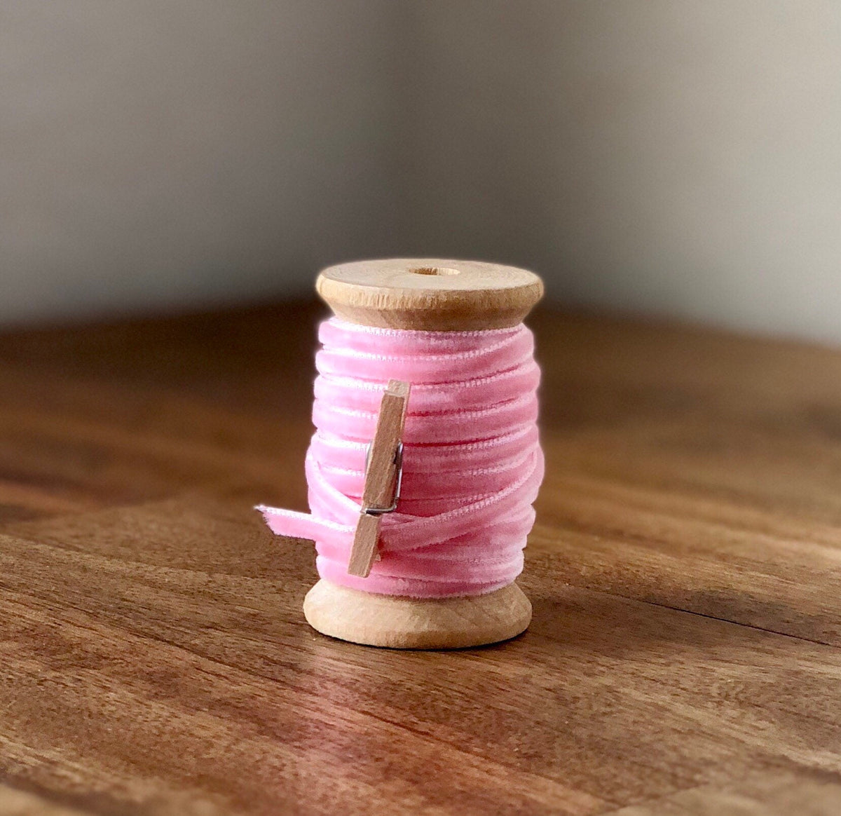 Thin pale pink velvet ribbon on wooden spool
