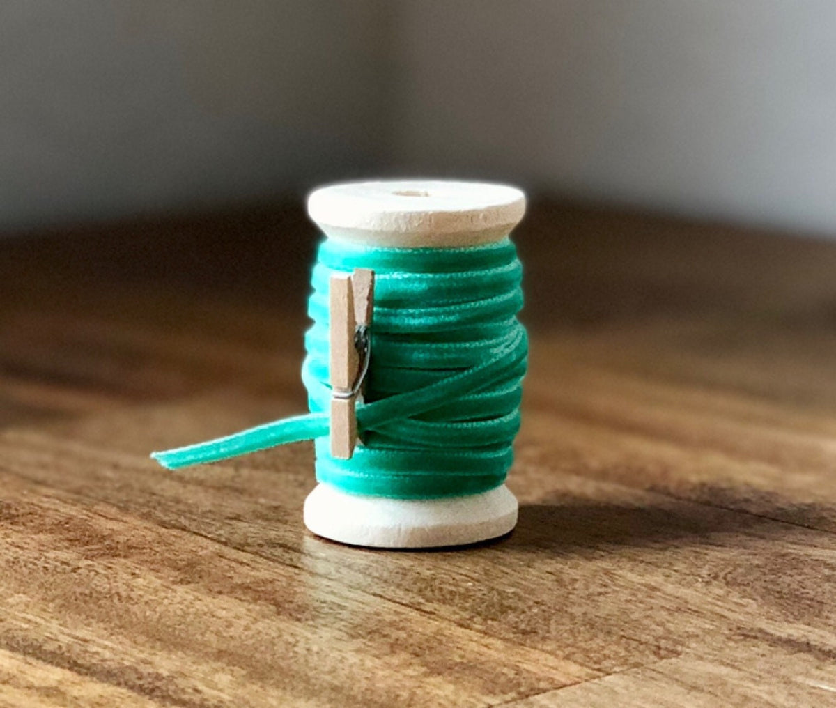 Thin mint green velvet ribbon on wooden spool