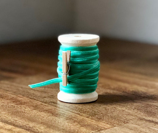 Thin mint green velvet ribbon on wooden spool