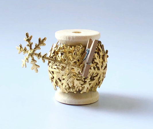 Gold snowflake ribbon trim on wooden spool