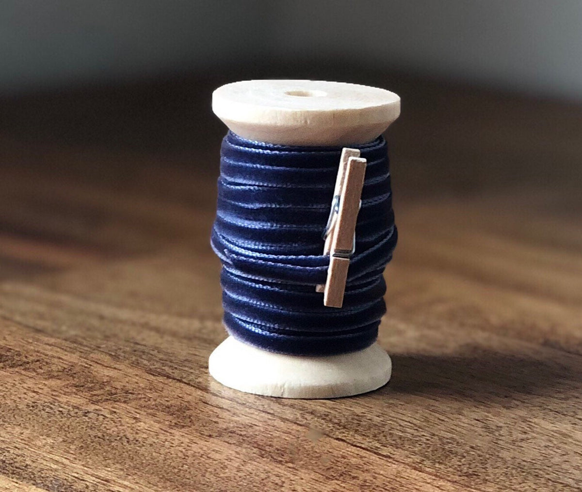 Thin navy blue velvet ribbon on wooden spool