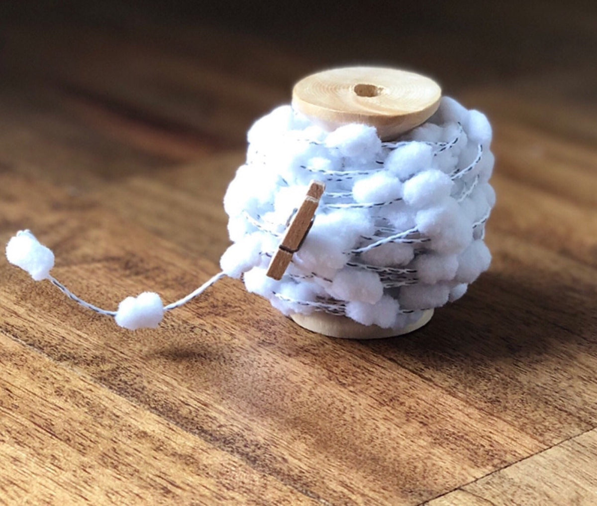 Wired pom pom ribbon trim on wooden spool, view 2