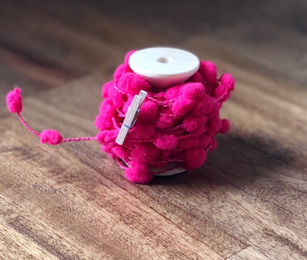 Wired pom pom ribbon trim on wooden spool, view 3