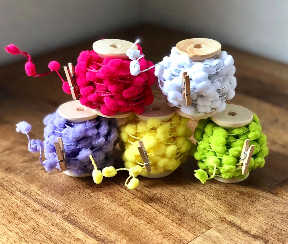 Wired pom pom ribbon trim on wooden spool