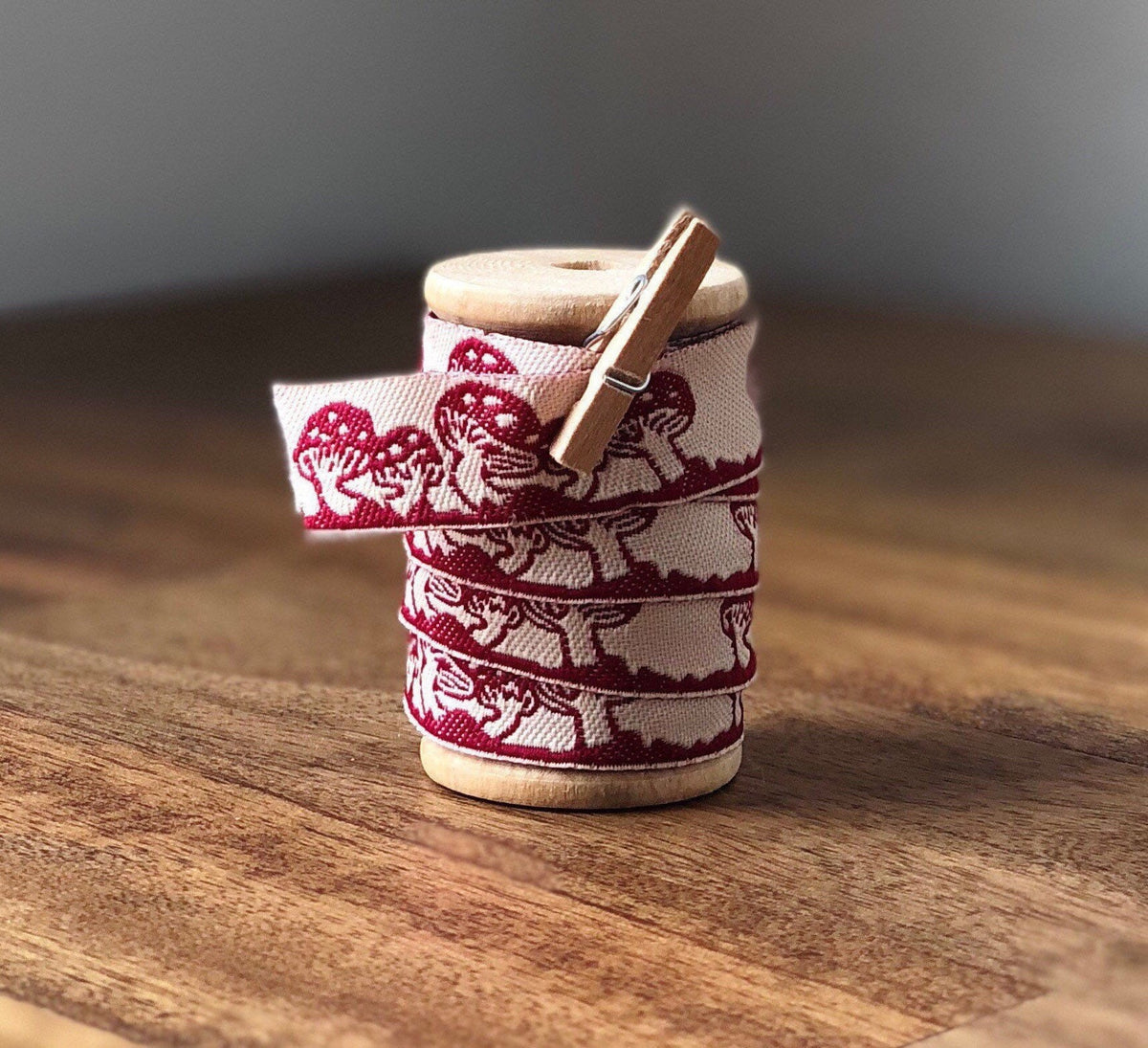 Embroidered red and white mushroom ribbon on wooden spool
