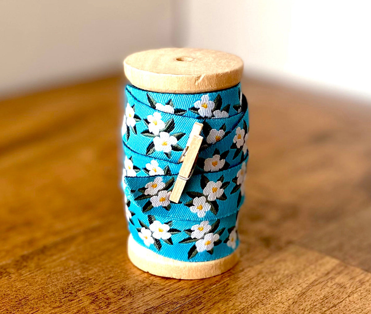 Embroidered blue dogwood flower ribbon on wooden spool