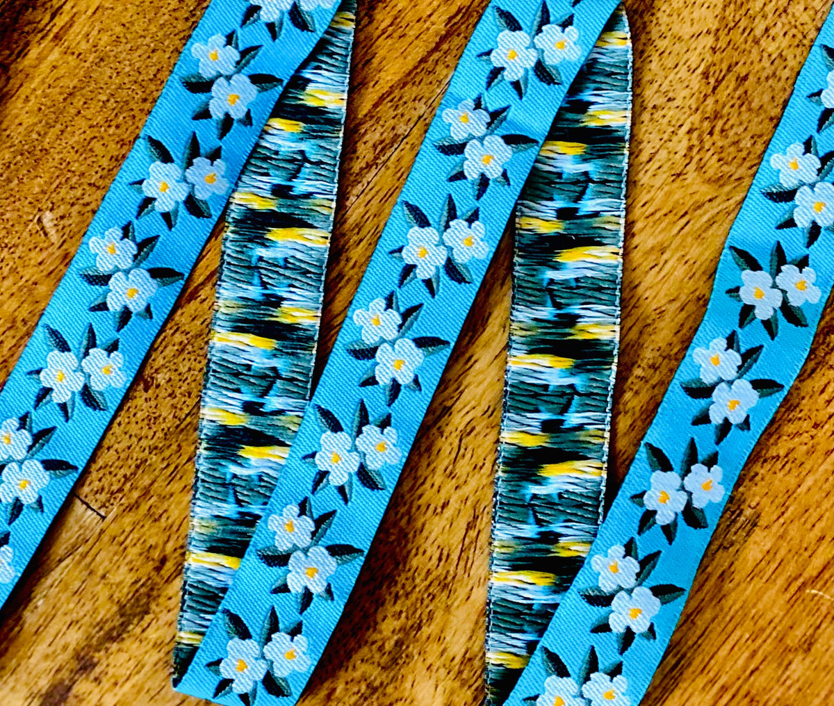 Embroidered blue dogwood flower ribbon on wooden spool, view 2