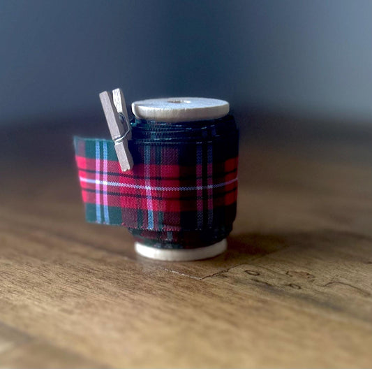 Red, green and white plaid satin ribbon on wooden spool
